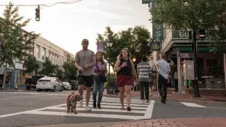 Family and dog walking across crosswalk in downtown Fredericksburg