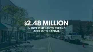 a picture of a city block with white text overlaid that reads: "$2.48 Million in Investments to Expand Access to Capital"